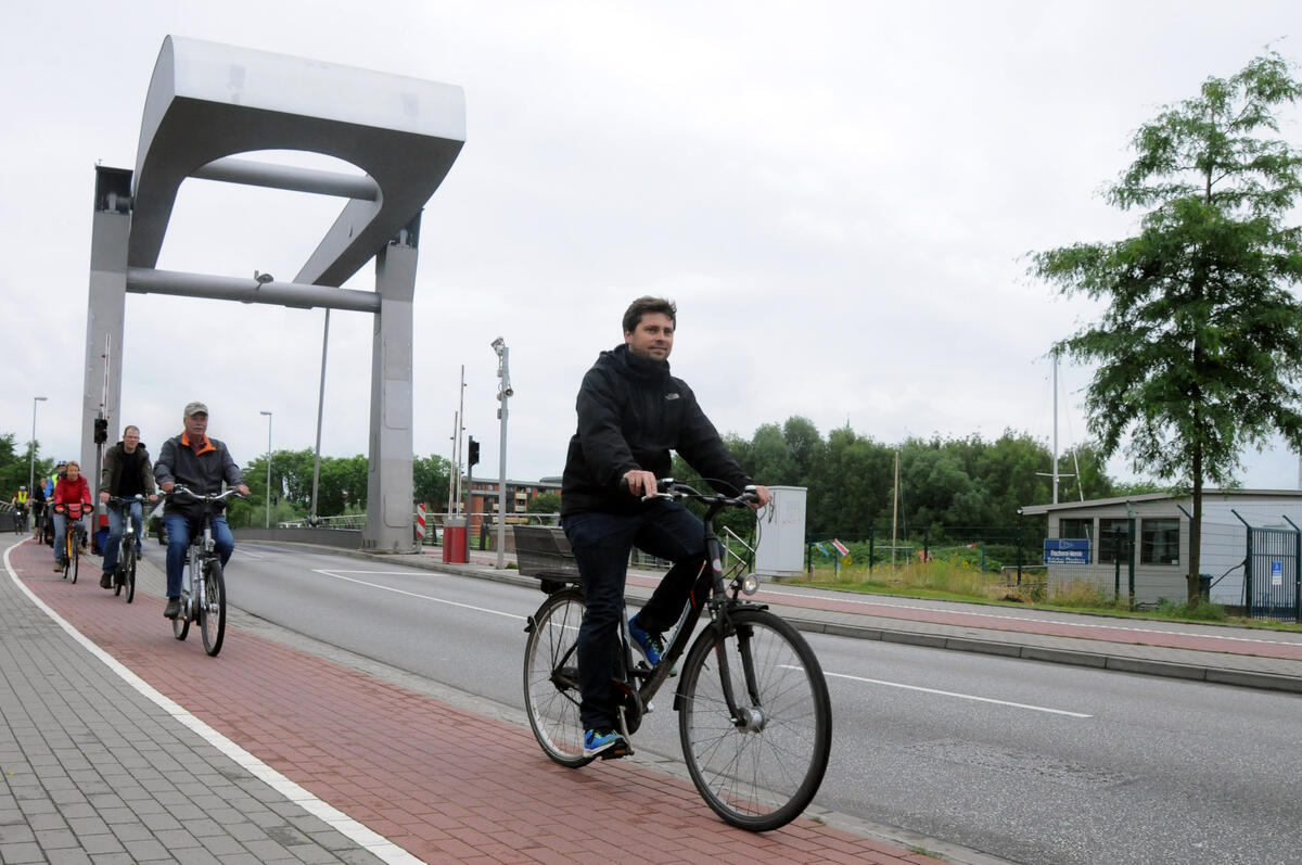 Bild vergrößern: Fahrradfahrer befahren den Radweg entlang der Hafenspange, die über die Käpten-Jürs-Brücke führt.
