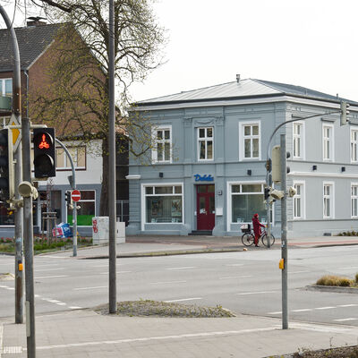 Das Foto zeigt die Verkehrskreuzung Reichenstraße / Westerstraße / Vormstegen / Klostersande. Im Bildmittelpunkt steht das sanierte Stadthaus Vormstegen 43. Das grau gestrichene Haus hat historische Fenster und ein neues Dach erhalten. 