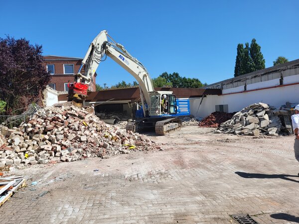 Bild vergr&ouml;&szlig;ern: Ein Bagger bei Abrissarbeiten auf einer gepflasterten Fl&auml;che.