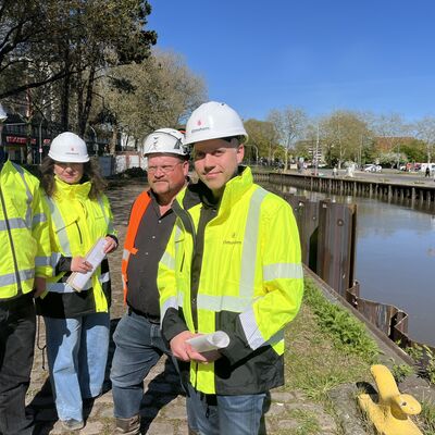 Elmshorns Baustadtrat Marius Munk mit Amtsleiterin Sybille Weinmann-Klinkow und den Unternehmensvertreter Steffen Haack sowie Marcus Behrens vom Ingenieurb&uuml;ro B&ouml;ger und J&auml;ckle an der neuen Spundwand am Hafen-Nordufer.