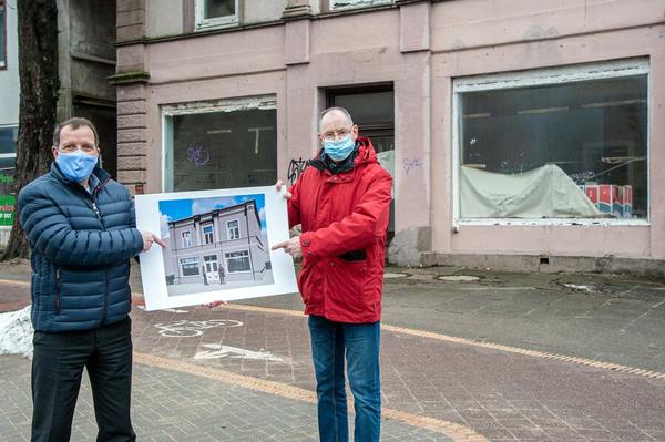 Bild vergrößern: Zwei Männer, Semmelhaack-Prokurist Arne Parchent und Baustadtrat Lars Bredemeier, stehen vor einem nicht sanierten Altbau und halten ein Plakat, auf dem die geplante Sanierung des Hauses gezeigt wird.